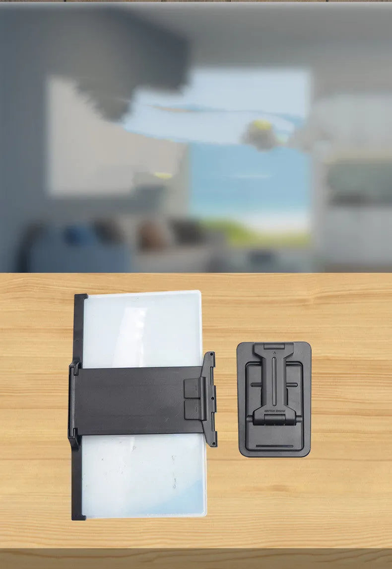 Black folding mobile phone screen magnifier with detachable phone holder on a desk.