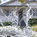 White cotton spider web Halloween decoration draped over a branch with plastic spiders.