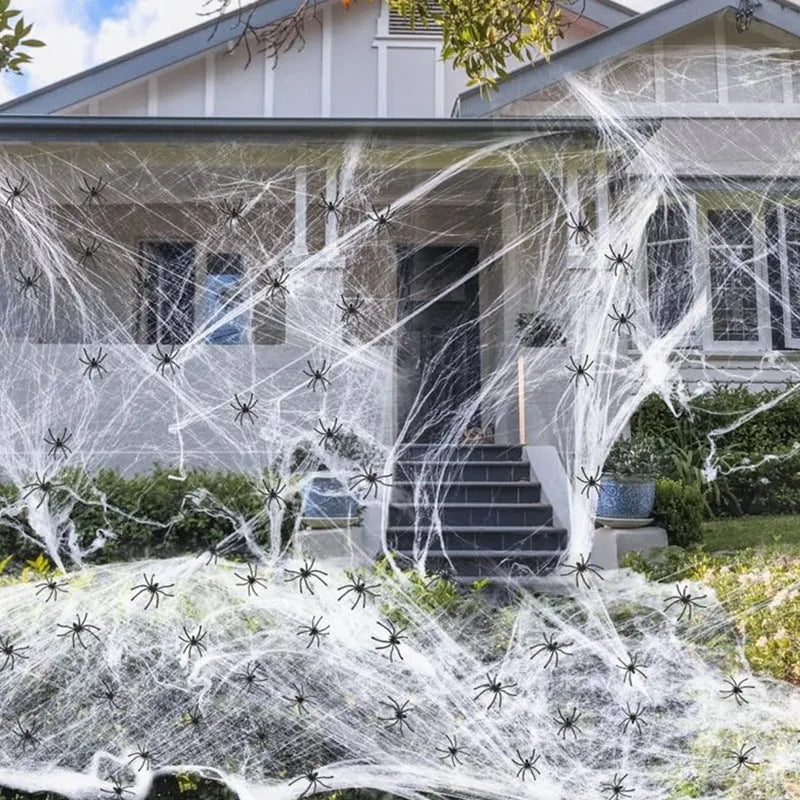 White cotton spider web Halloween decoration draped over a branch with plastic spiders.