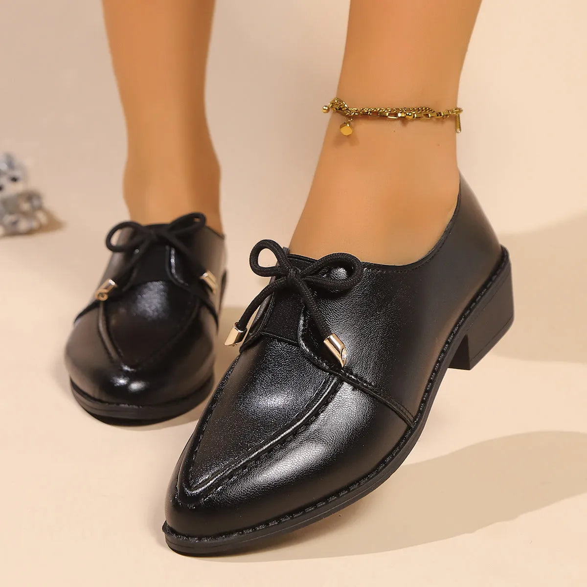 Women's beige loafers with a large decorative bow, showcasing rounded toe and slip-on design.