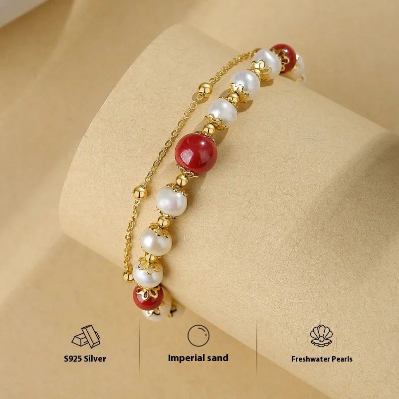 Sterling silver double-layer bracelet with cinnabar red bean and freshwater pearl beads, electroplated finish, geometric bean shape on white background