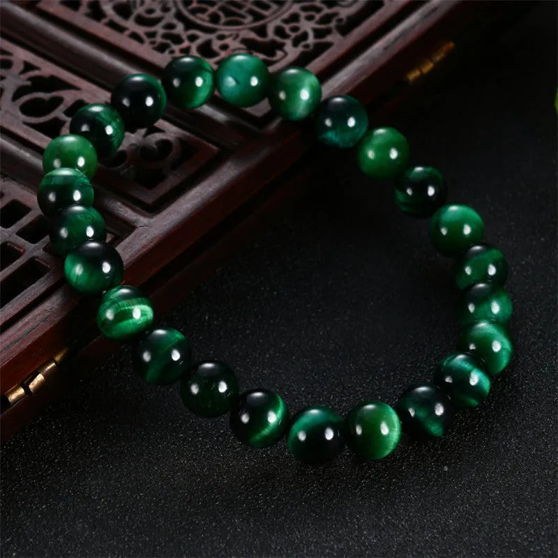 Green tiger eye stone bracelet with polished geometry beads and a sliding knot closure on a wrist.