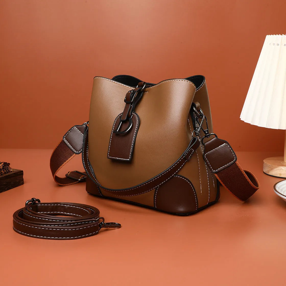 Women's soft PU bucket bag with tassel and contrast colour stitching on a plain background