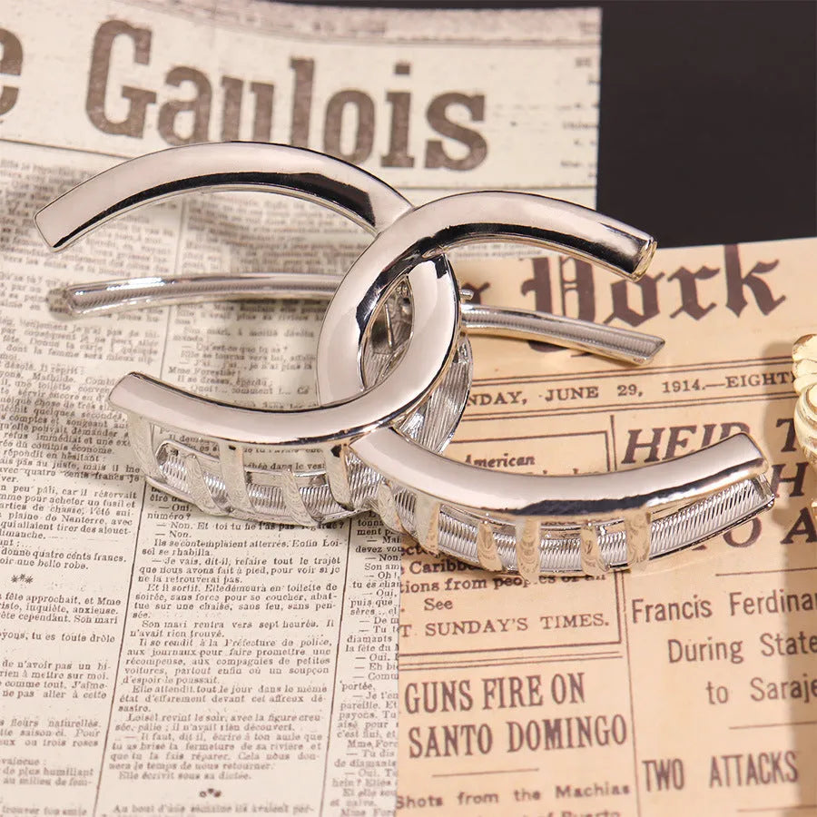 Assorted silver metal hair claws and barrettes including wave, knot, bow, and pearl designs on a white background.