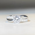Silver geometric twist band ring with a 1-carat Moissanite stone in a four-claw setting.