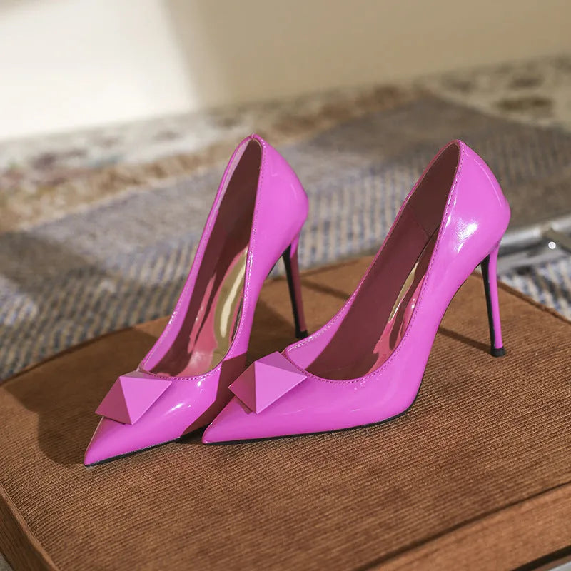 Women's pink patent leather pointed toe stiletto heels with buckle closure and rivet details