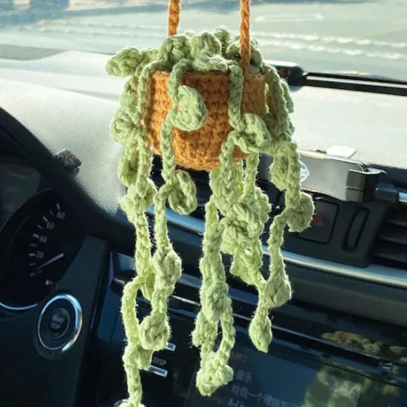Green and white knitted wool car plant decoration with macramé texture and a white hanging rope.