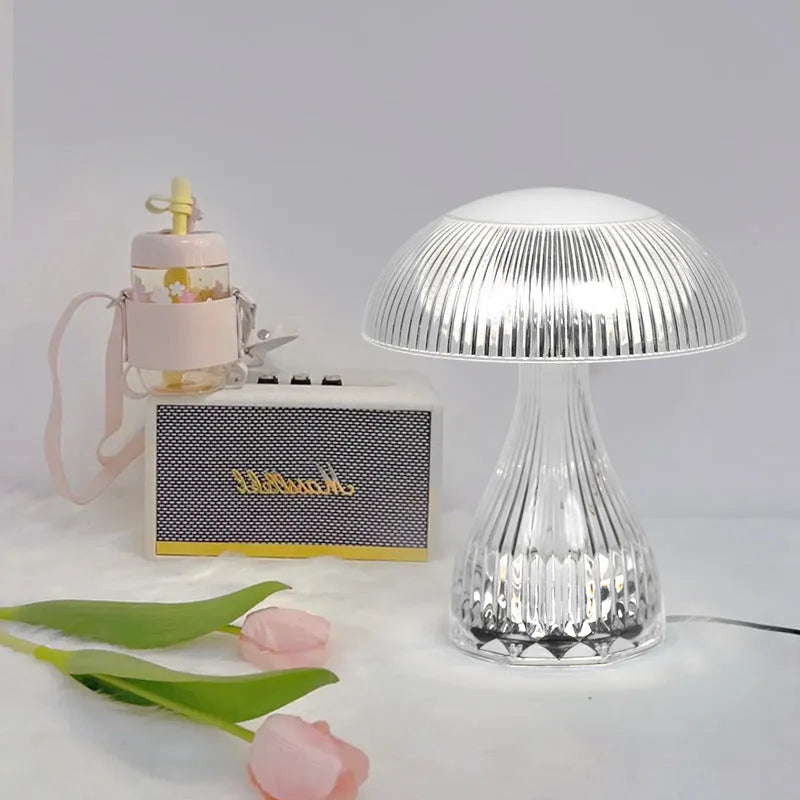 Small white rechargeable touch night lamp with acrylic body and plastic base on a wooden table.