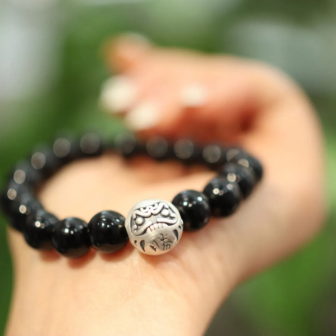 Black agate bracelet with 10mm beads and a sterling silver clasp on a wrist.