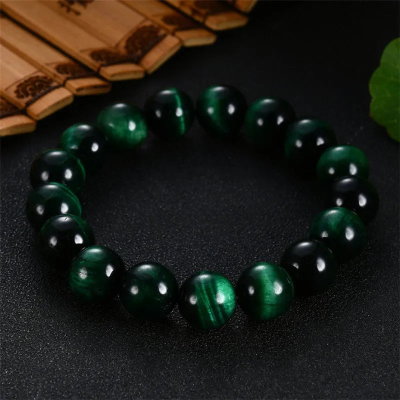 Green tiger eye stone bracelet with polished geometry beads and a sliding knot closure on a wrist.