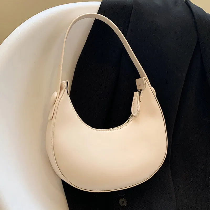 Women's retro dumpling-shaped PU leather shoulder bag in black showing sandwich pockets and zippered compartment