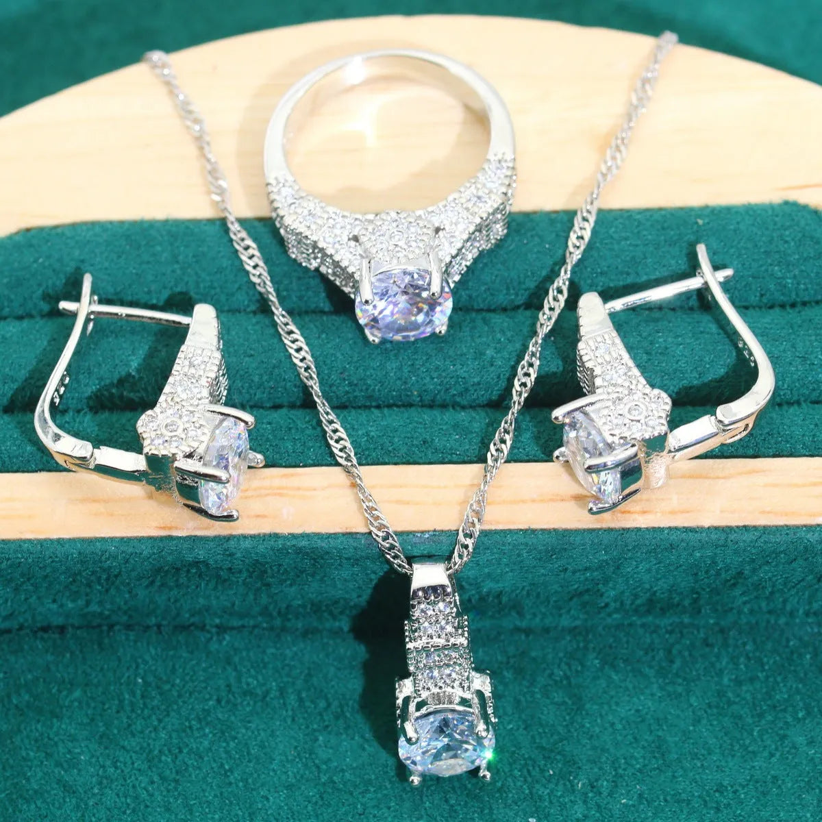 Four-piece bridal jewellery set showing zirconium alloy necklace, earrings, ring, and bracelet in water wave chain design.