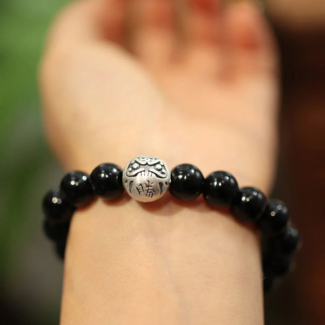 Black agate bracelet with 10mm beads and a sterling silver clasp on a wrist.