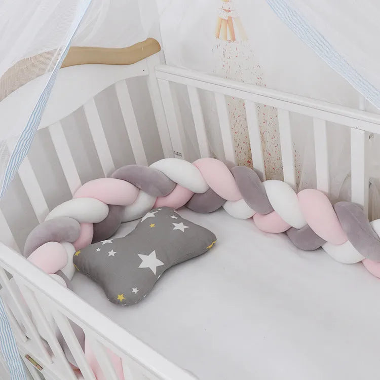 Braided knot crib bumper in spandex velvet, shown bending to fit a white wooden cot.