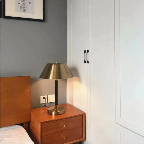 Post-modern metal bedside lamp with antique copper finish on a bedside table