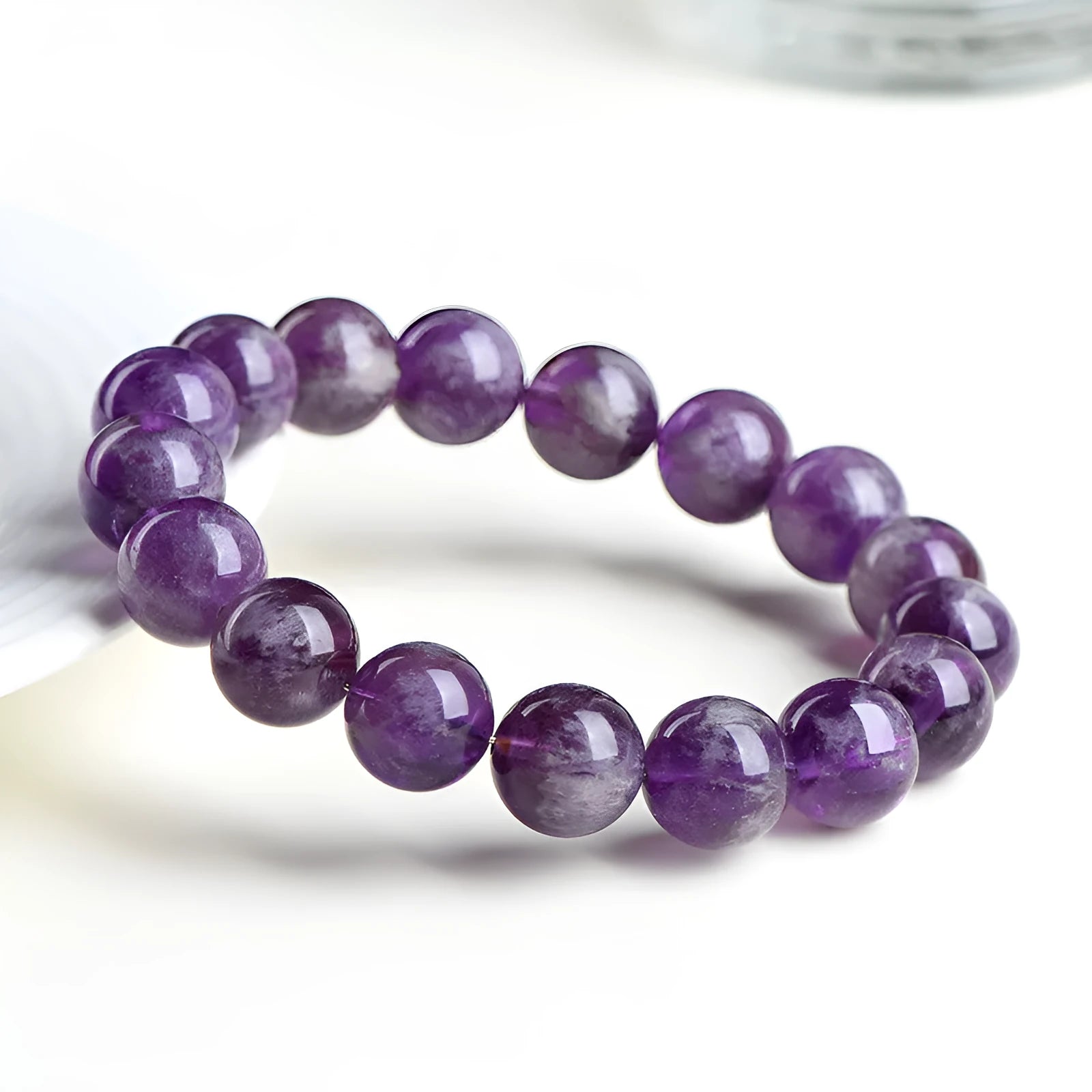 Natural feather amethyst crystal bracelet with scattered purple beads on a white background.