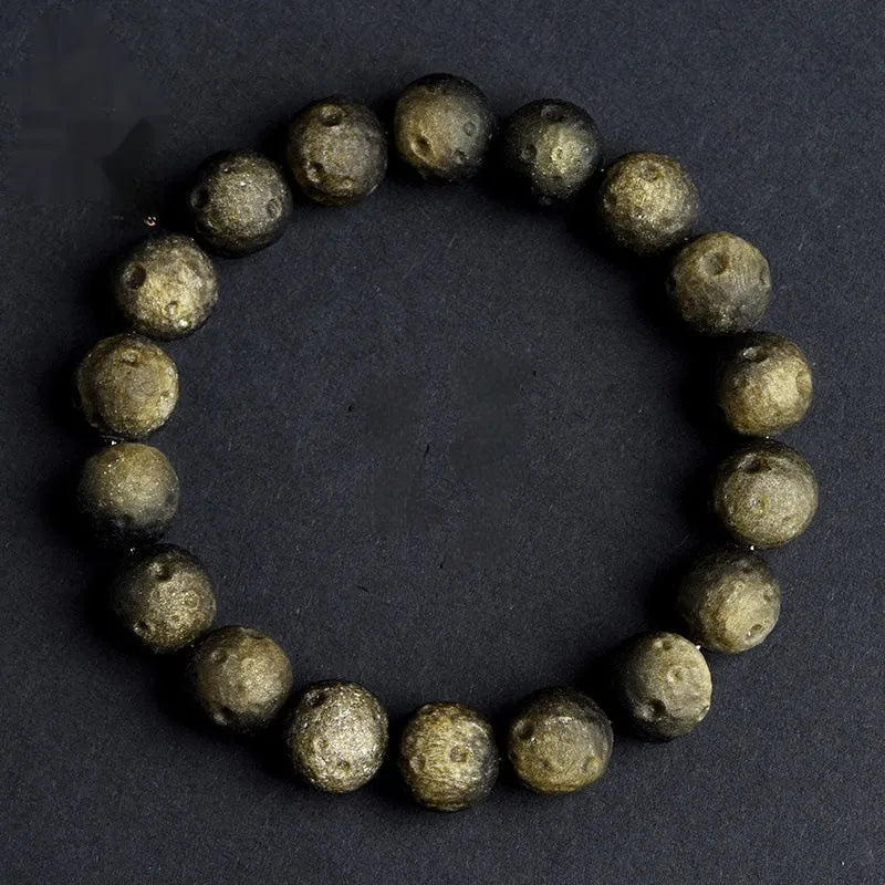 Natural obsidian crater ball bracelet with meteorite-like texture in silver stone or gold finish.