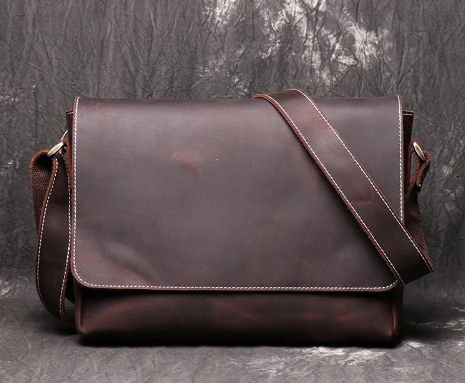 Men's vintage brown leather messenger bag with adjustable strap, shown open to reveal internal organiser pockets.