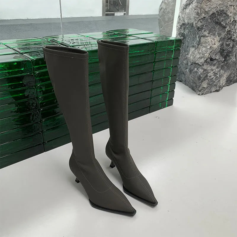 Black women's knee-high pointed toe boots with a stiletto heel and back zip fastening.