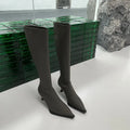 Black women's knee-high pointed toe boots with a stiletto heel and back zip fastening.