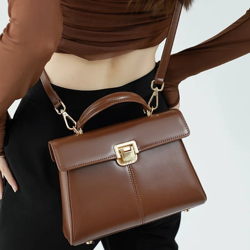 Women's black leather shoulder bag with vachette clasp showing internal compartments and adjustable strap