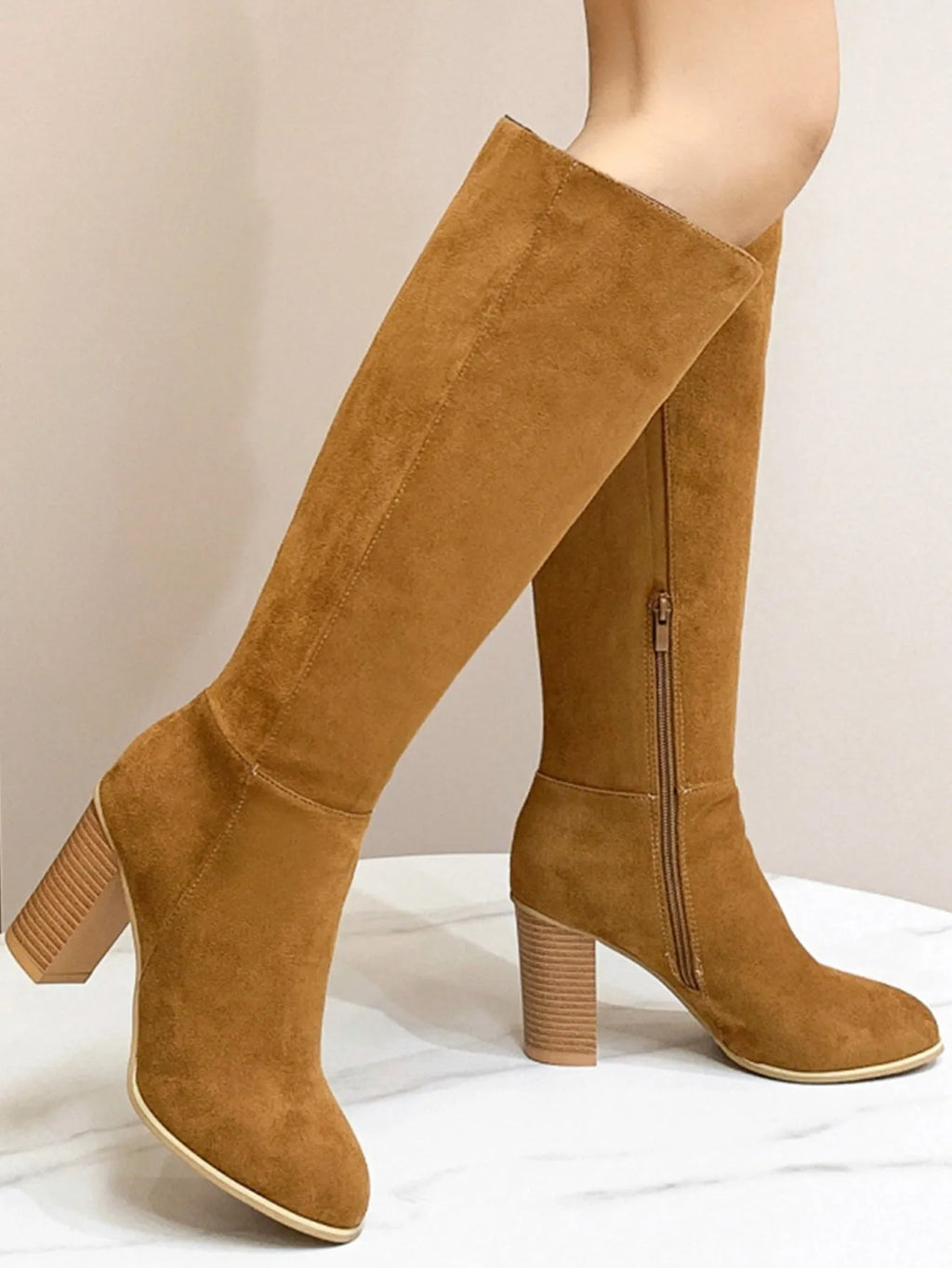 Black square toe high heel fashion boots for women on a plain background.
