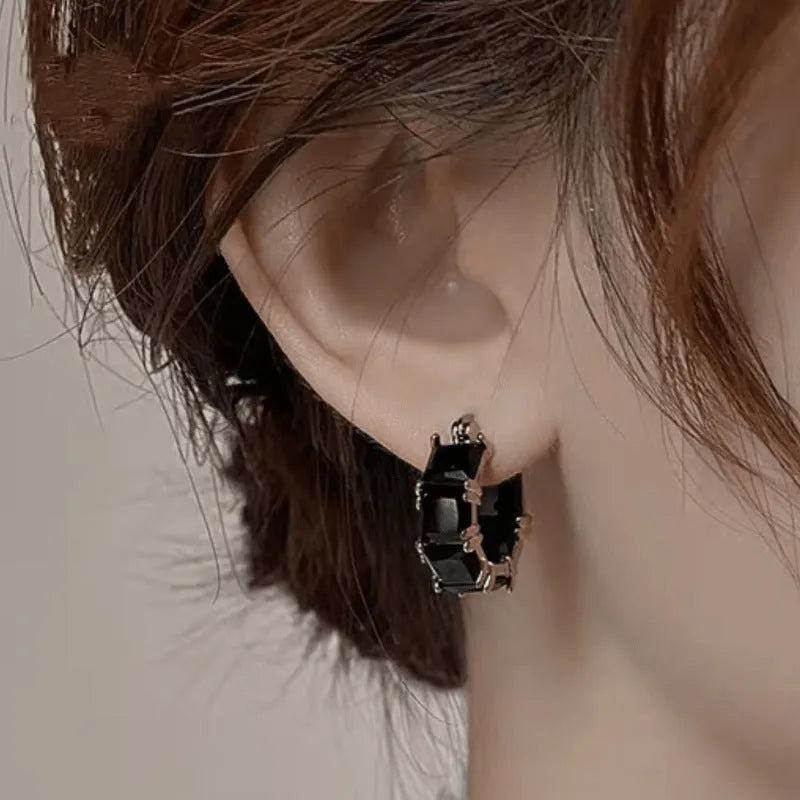 Geometric U-shaped gold-tone earrings with black zircon stones, approximately 20mm diameter