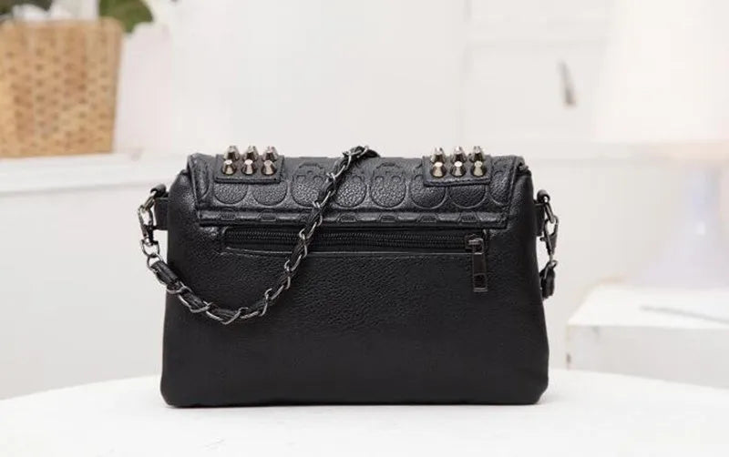 Black leather messenger bag with skull rivets and buckle closure for women