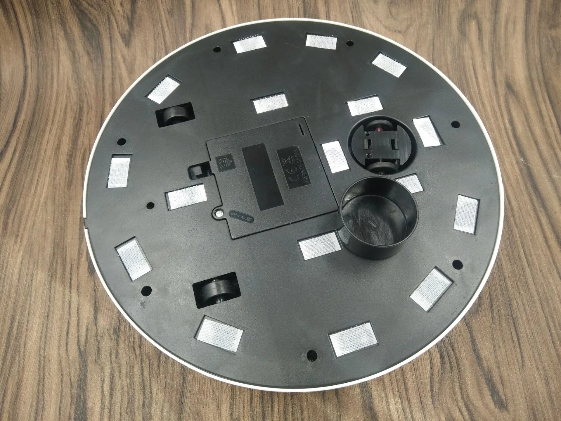 Black or white ABS plastic robot vacuum cleaner on a hardwood floor.