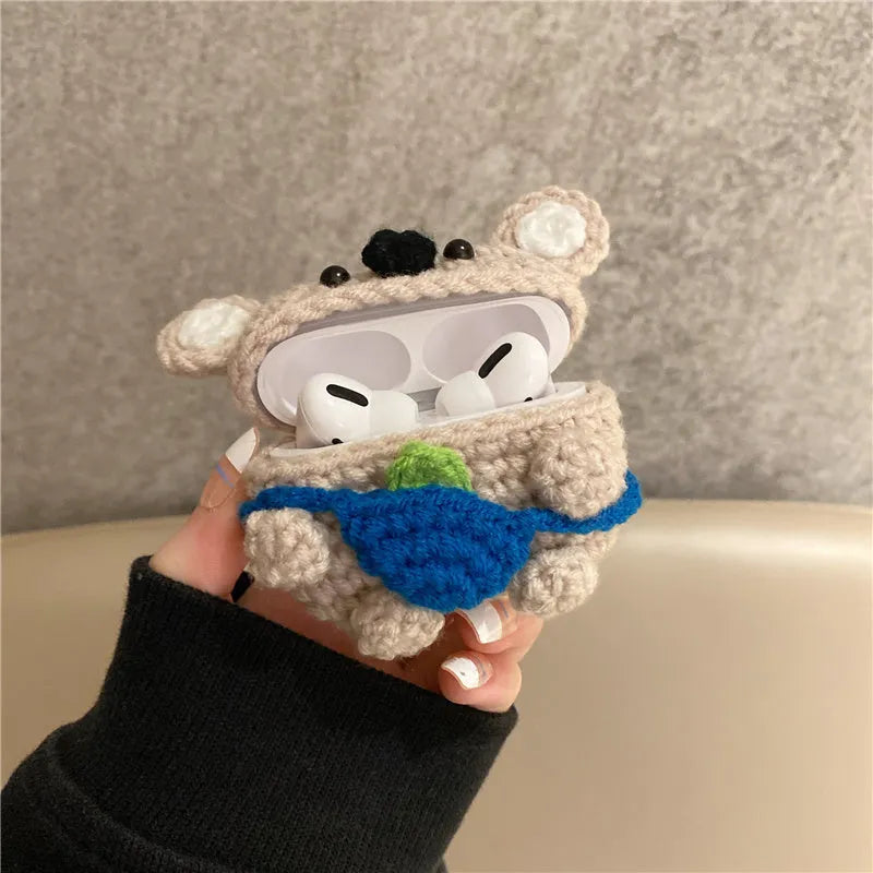 Handmade knitted koala bear backpack cover for Apple Airpods case on a table.