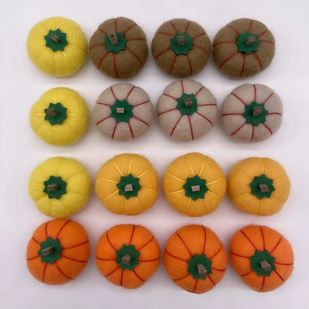 Wool felt pumpkin-shaped doll decorations in autumn colours on a neutral background