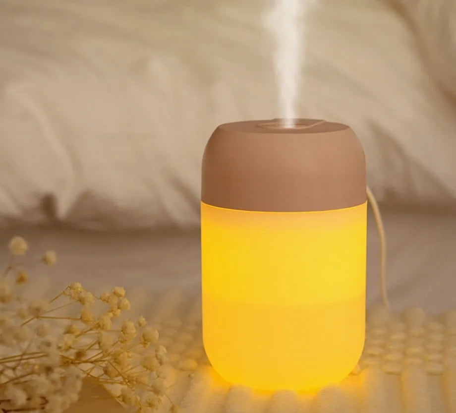 White cylindrical USB-powered mini humidifier with aromatherapy function on a desk.