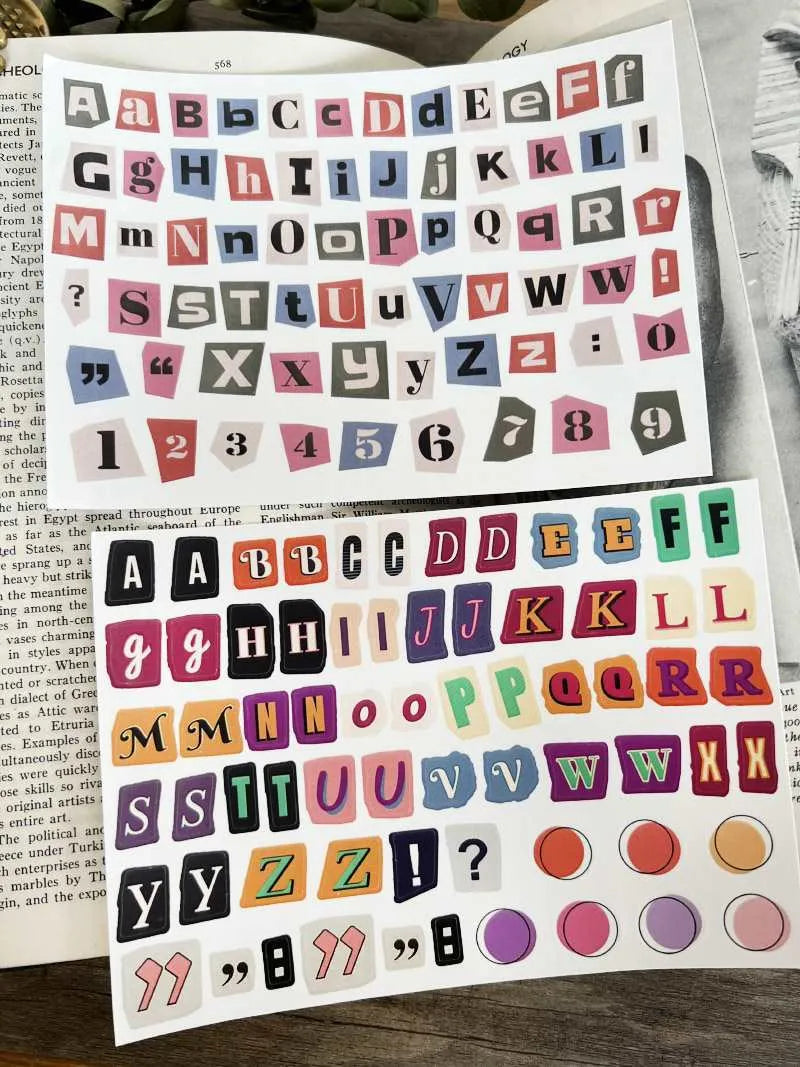 Set of printed cute-style stickers showing English letters A, B, C, D, E, numbers, symbols, and weekly words on a sheet.