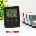 Black and white magnetic kitchen timer with countdown and count-up display on a refrigerator.