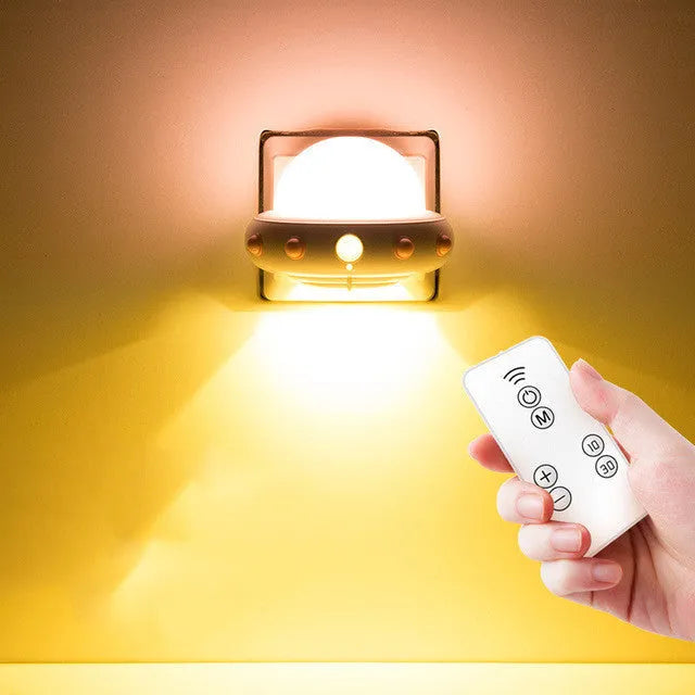 Blue UFO-shaped bedside night light with remote control on a wooden table.