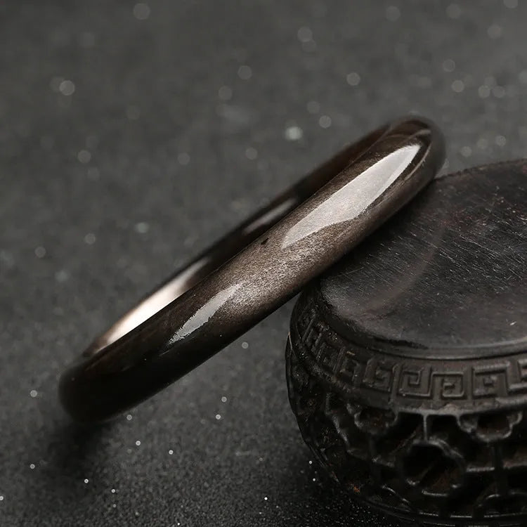 Natural silver stone cat's eye obsidian and alloy ethnic bracelet with geometric patterns on a wrist.