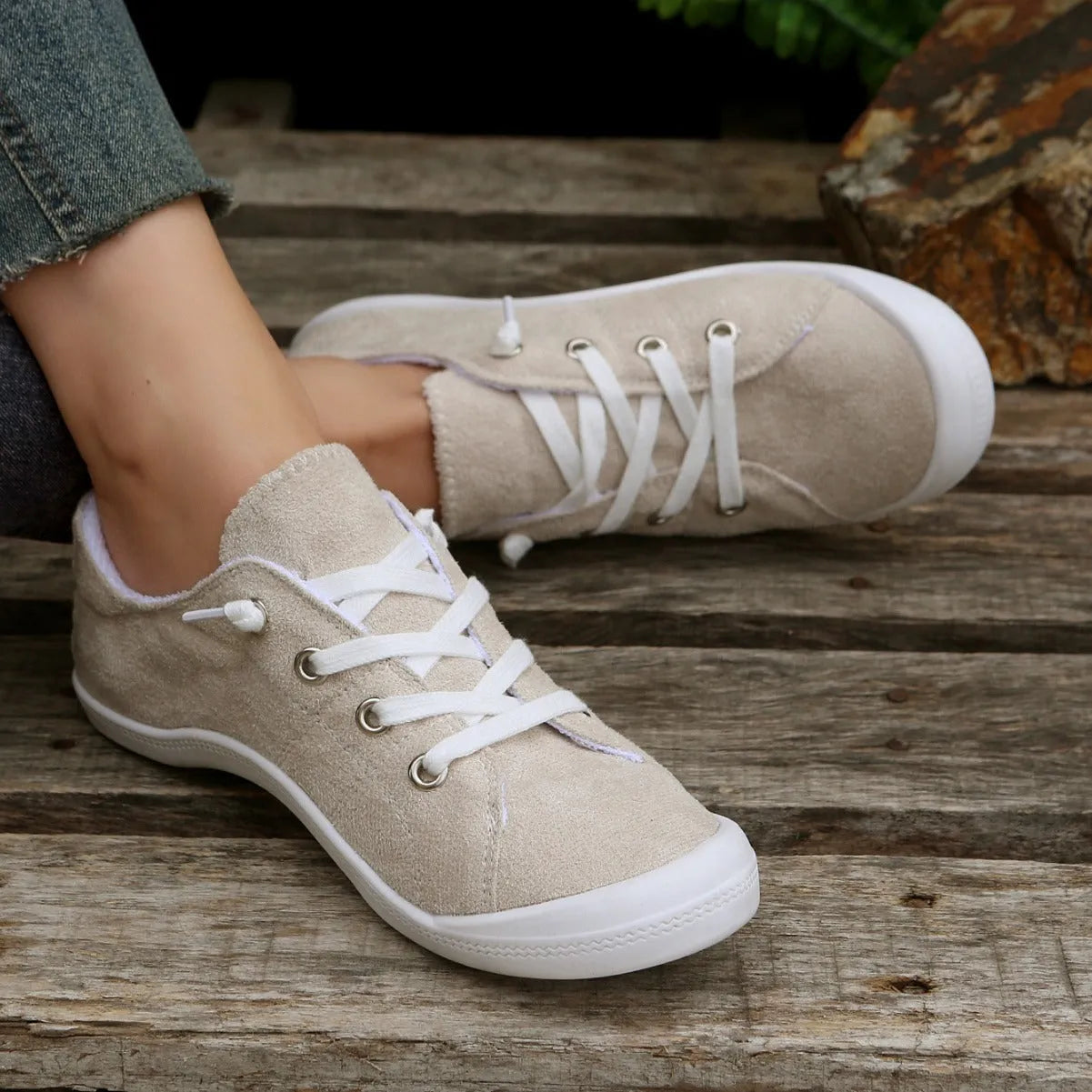 Women's creamy-white low-top fabric sneaker with rubber sole on a neutral background.