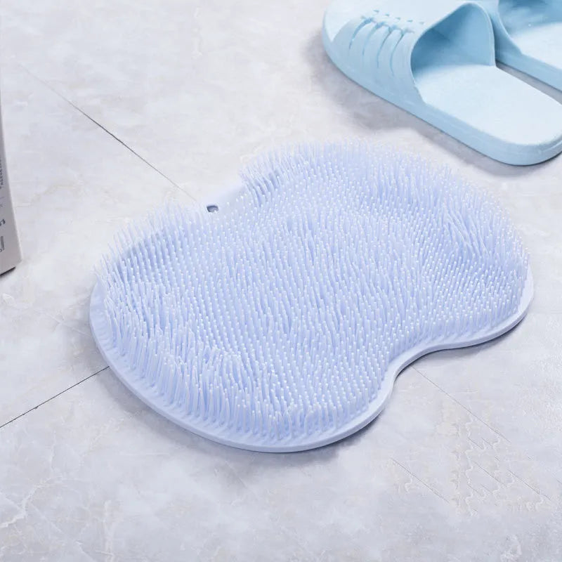 Orange TPR bath brush with silicone bristles and suction cups on base, shown on bathroom tiles.