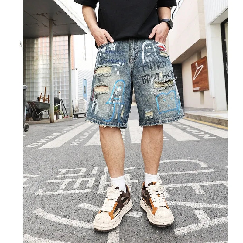 Men's blue ripped denim shorts with graffiti design and straight leg.