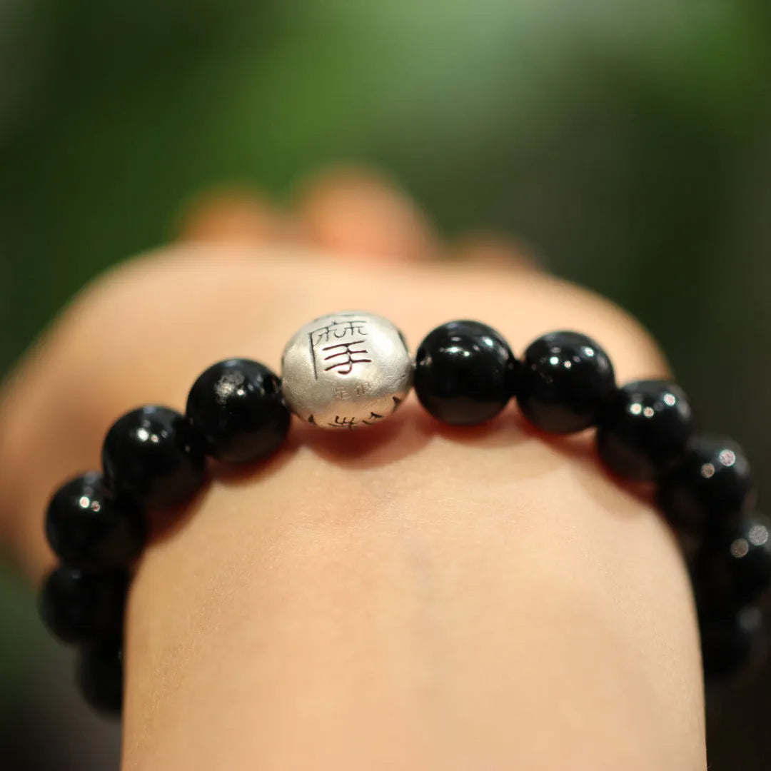 Black agate bracelet with 10mm beads and a sterling silver clasp on a wrist.