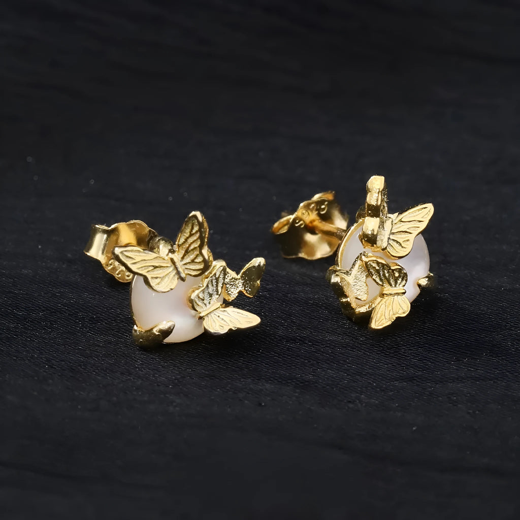 Close-up of a pair of silver butterfly stud earrings with a gold-toned finish.