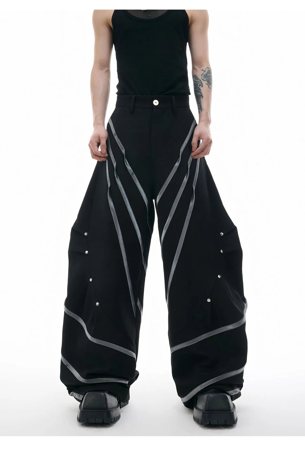 Men's black and white deconstructed trousers with metal striped rivets and front pleats.