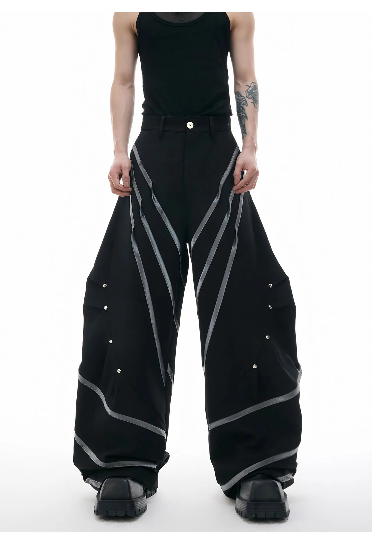 Men's black and white deconstructed trousers with metal striped rivets and front pleats.