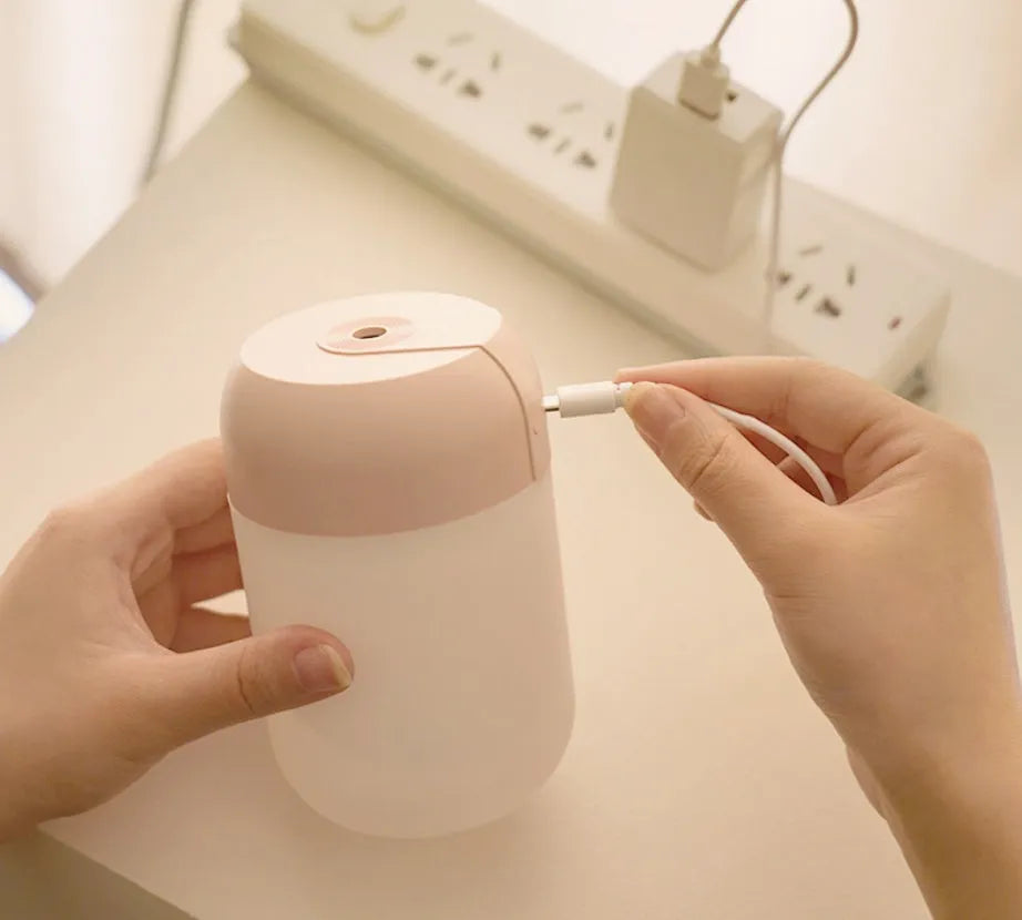 White cylindrical USB-powered mini humidifier with aromatherapy function on a desk.