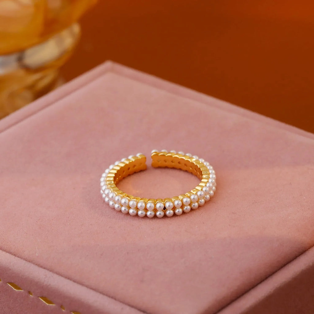 Gold electroplated open mouth geometry pearl ring for women on a neutral background.