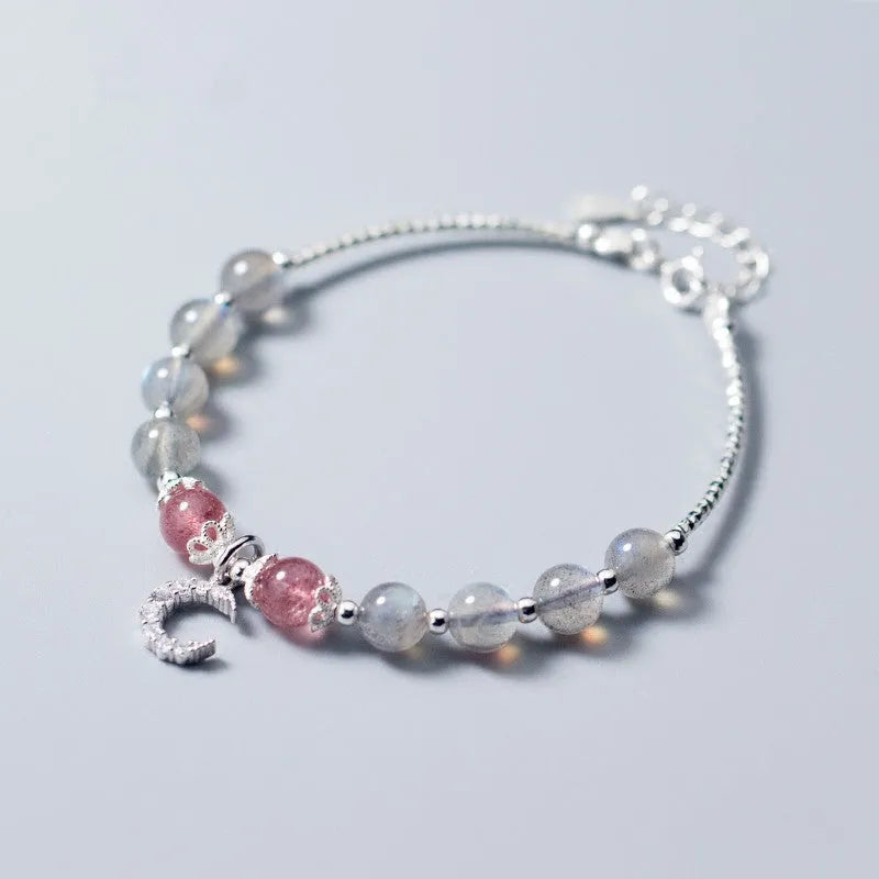 Adjustable natural moonstone bracelet with crescent moon charm on a wrist, showing extension chain.