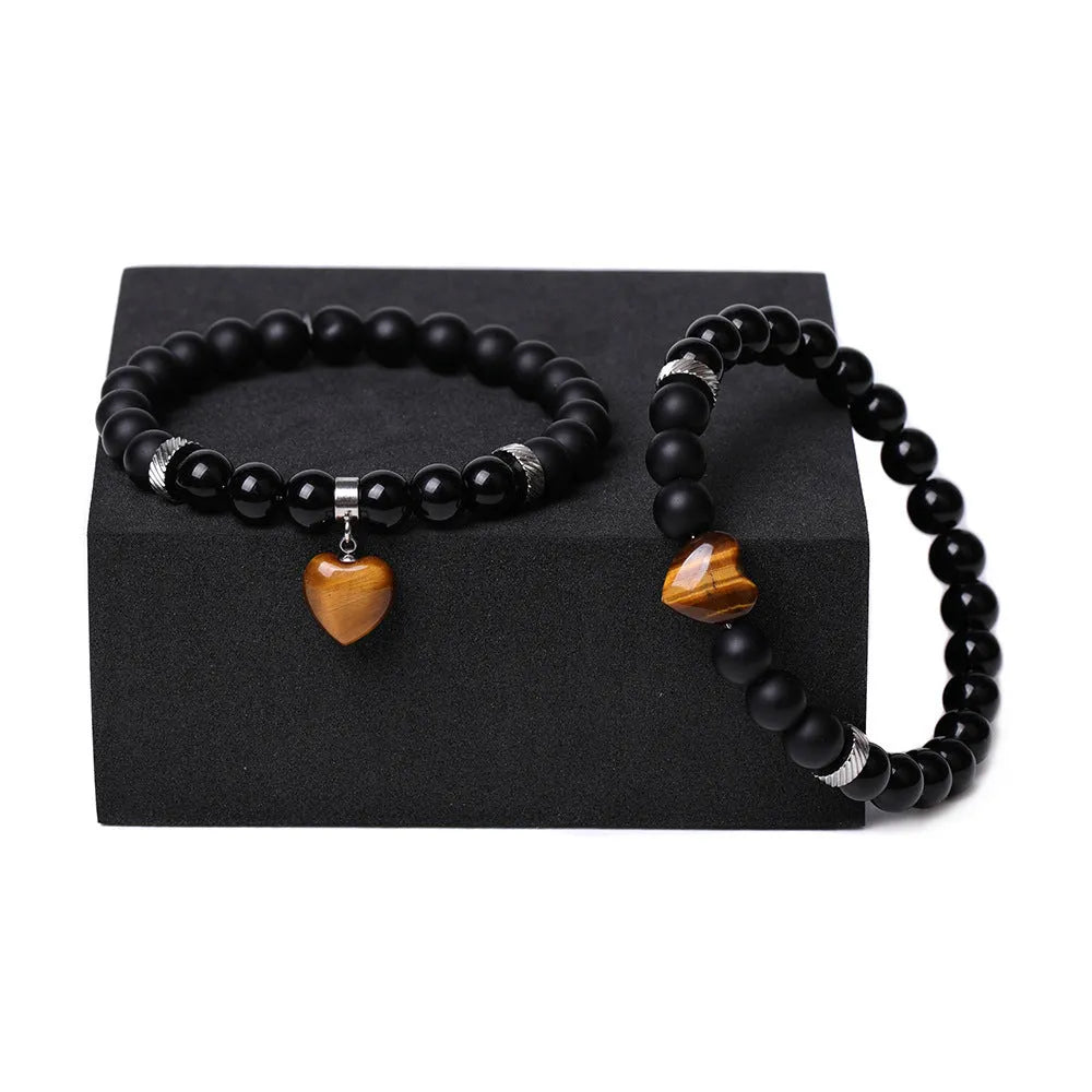 A pair of matching bracelets with polished geometric heart pendants made from natural stone.