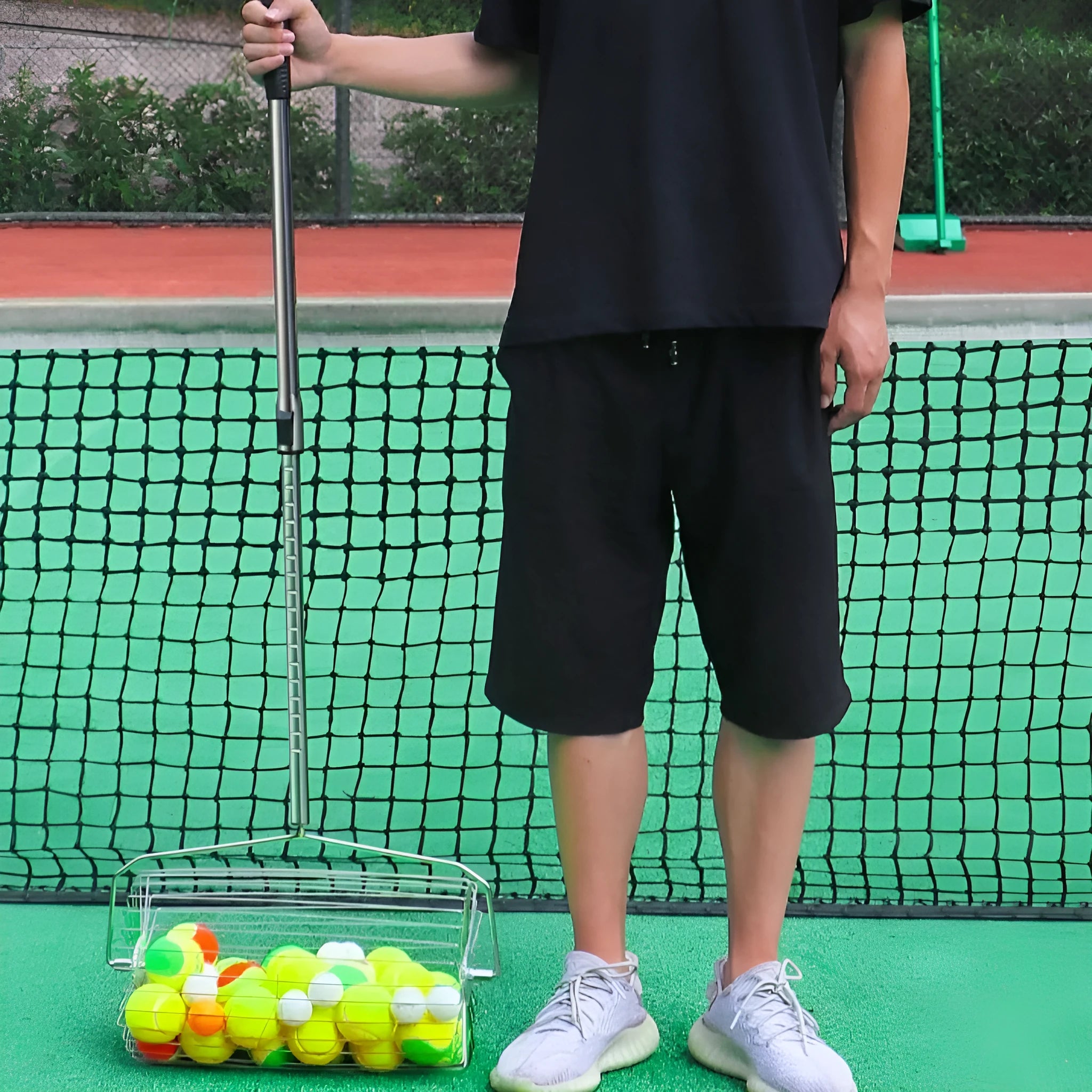 Stainless steel tennis ball picker roller with adjustable handle on a tennis court