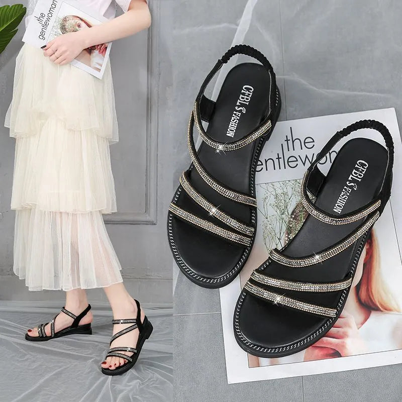 Women's silver flat sandals with rhinestone decoration and an elastic band, showing the round toe and rubber sole.