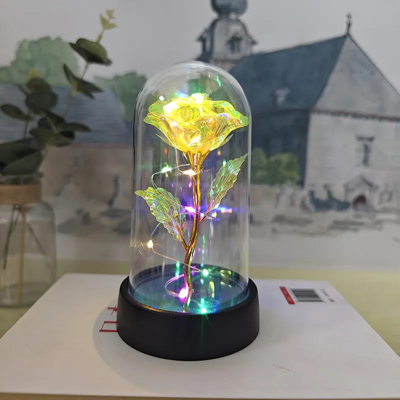 Small decorative night lamp with glass cover, plastic flower, and black base on a pink box.